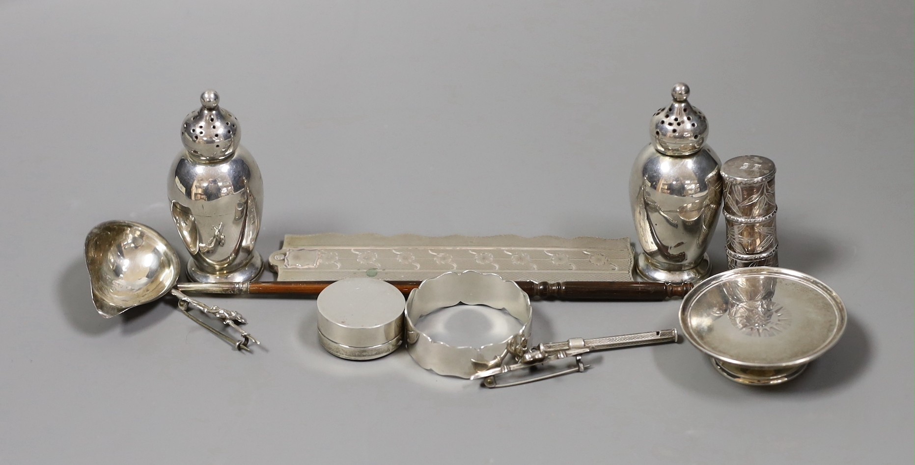 A quantity of small silver or white metal items including a long handled server spoon, Chinese pepperette, pair of Victorian pepperettes, Victorian silver paten, 19th century toddy ladle by Taylor & Perry, folding comb,